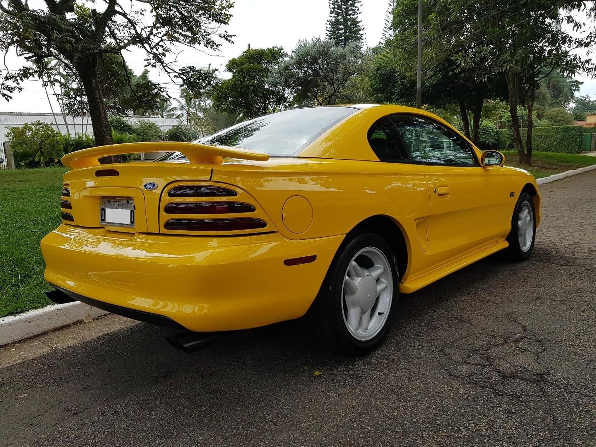 Ford Mustang 5.0 Gt Coupe amarelo visto de traseira com a lanterna em três seções horizontais e aerofólio acima da tampa do porta-malas