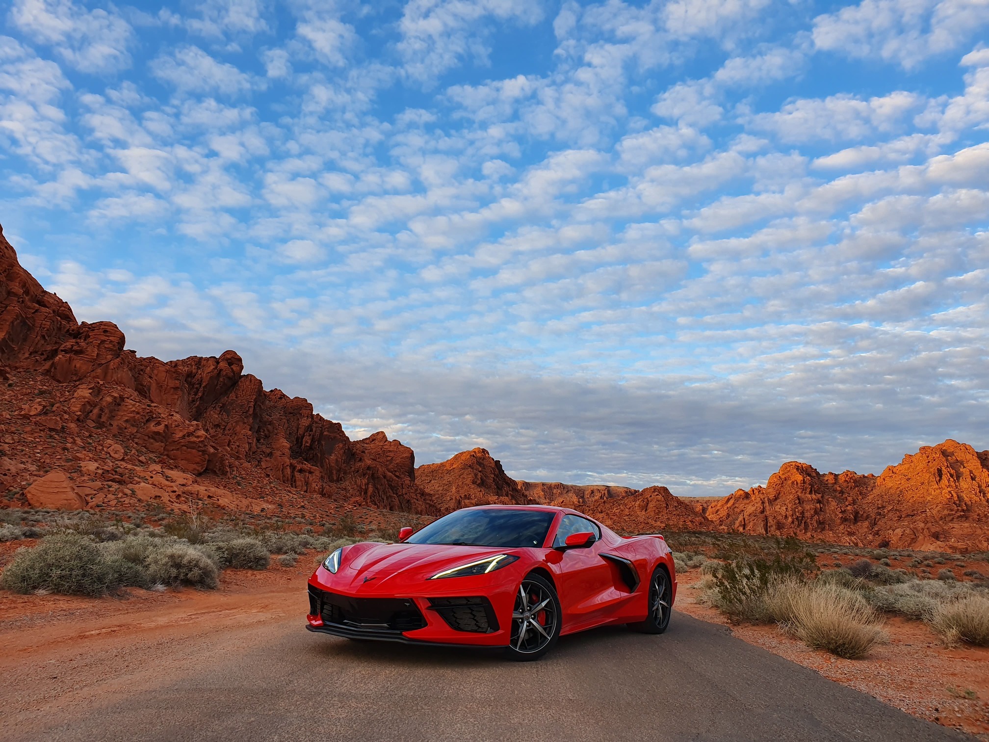 Chevrolet Corvette 2020 vermelho na estrada parado de frente em região desértica e ao alto um céu azul com algumas nuvens