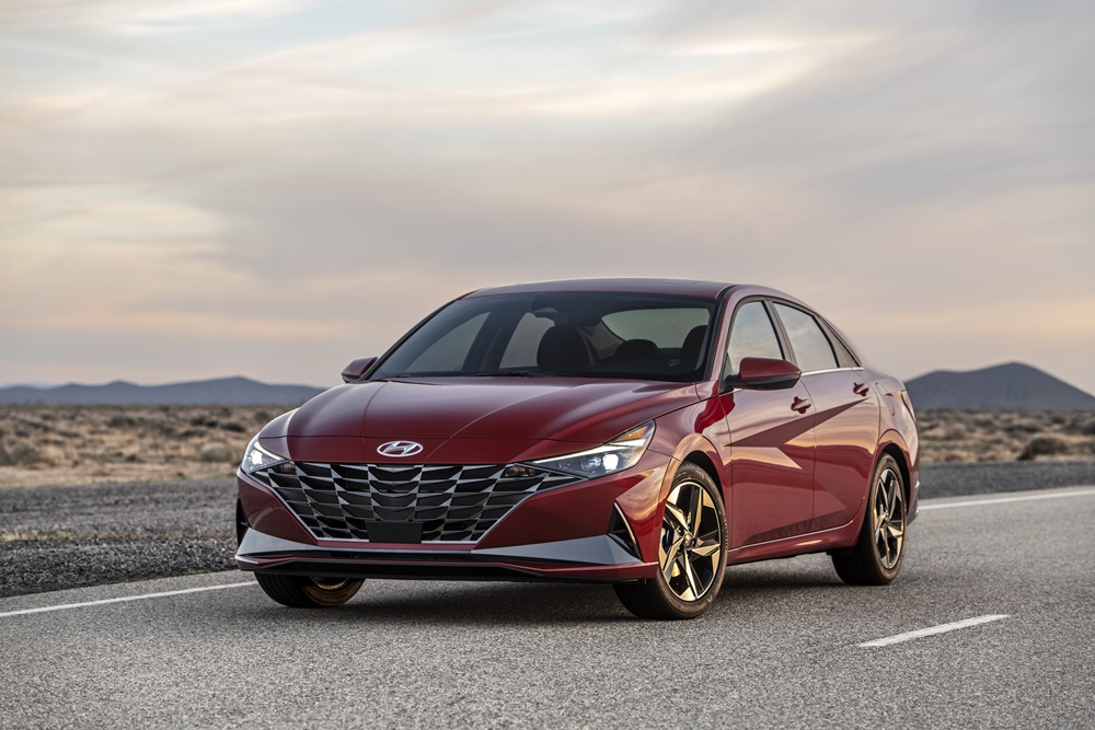 Novo Hyundai Elantra vermelho de frente estacionado com luzes diurnas acesas e ao fundo o deserto e a estrada