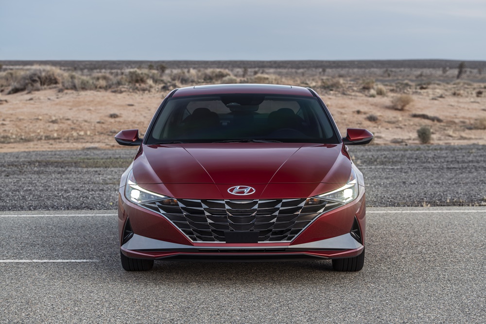 Novo Hyundai Elantra vermelho estacionado de frente tem grade rebaixada em forma de sorriso e lanternas que lembram bumerangues e se propagam pelas extremidades do carro