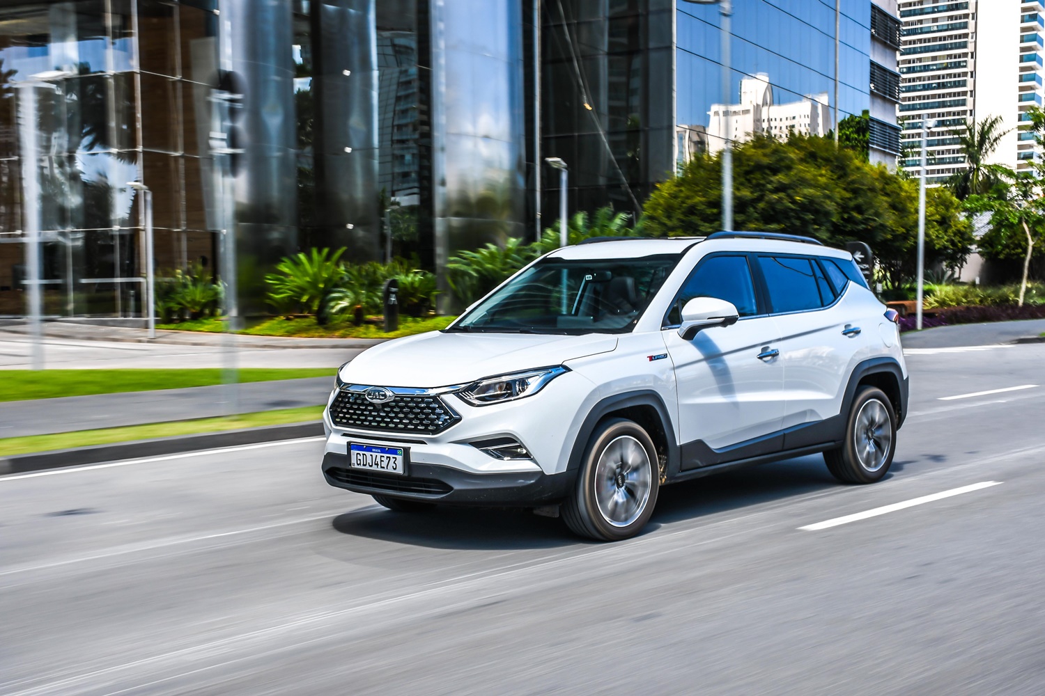 Jac T60 branco em movimento na rua com prédios comerciais espelhados ao fundo