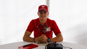 Mick Schumacher, filho de Michael Schumacher, posa para foto com boné vermelhor e camisa vermelha