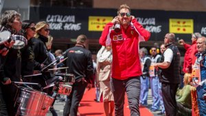 Sebastian Vettel com jqueta da ferraroi e fones nos ouvidos caminhando